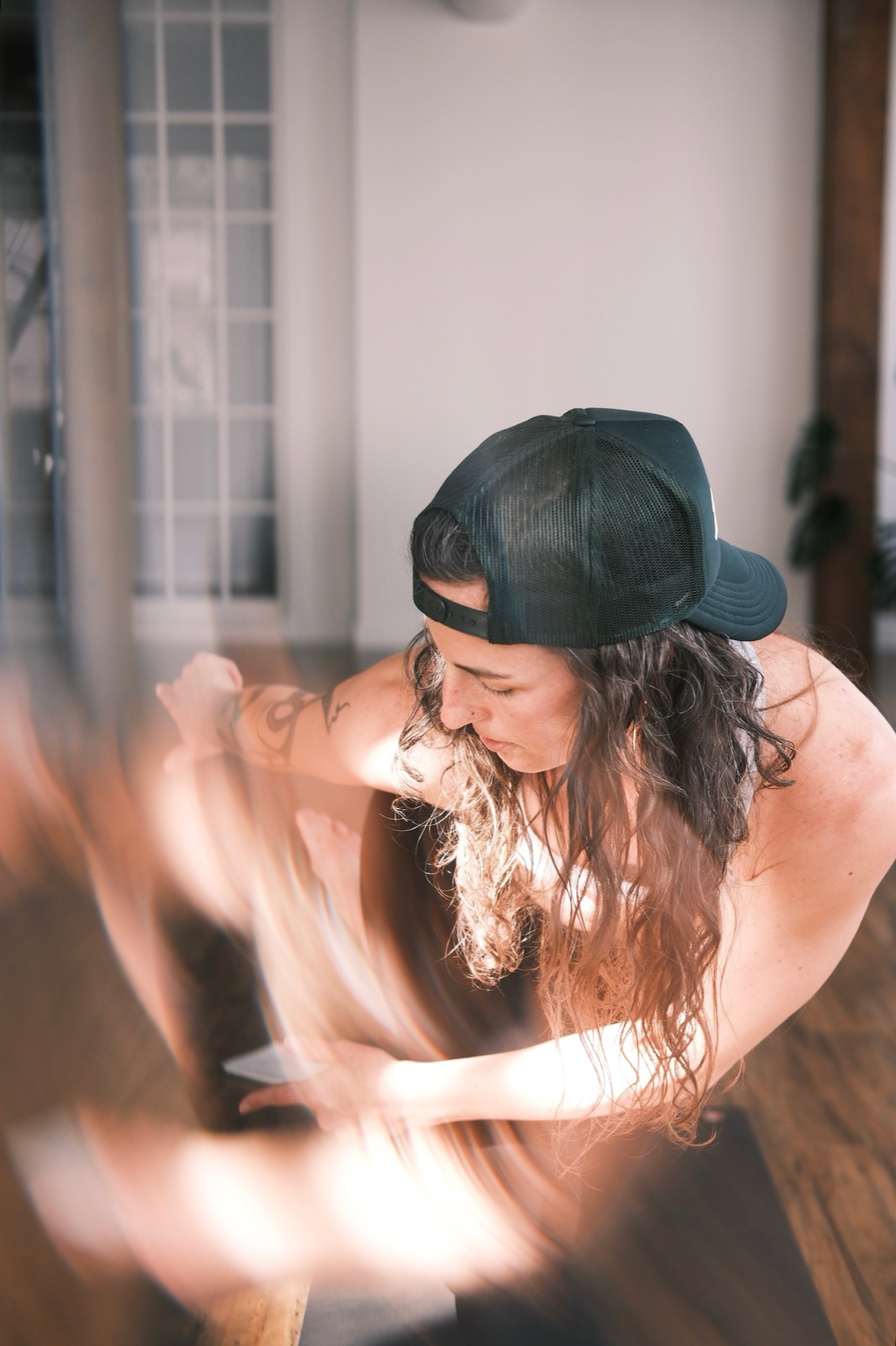 Bonnie Weeks mid-movement on her mat, arms blurred with motion in warm light